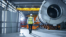 Un homme portant un casque de construction se déplace dans une installation énergétique industrielle.