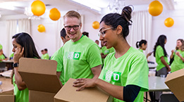 Employees wearing green shirts while packing boxes. 