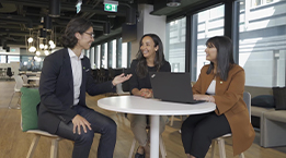 Three businesspeople with diverse ethnicities sitting around a table.