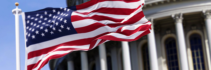 A closeup of a flying American flag in front of a federal government building.