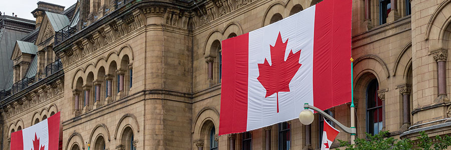 A large Canadian flag displayed outside a government building.