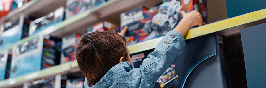 A child in a toy store reaching for a toy.