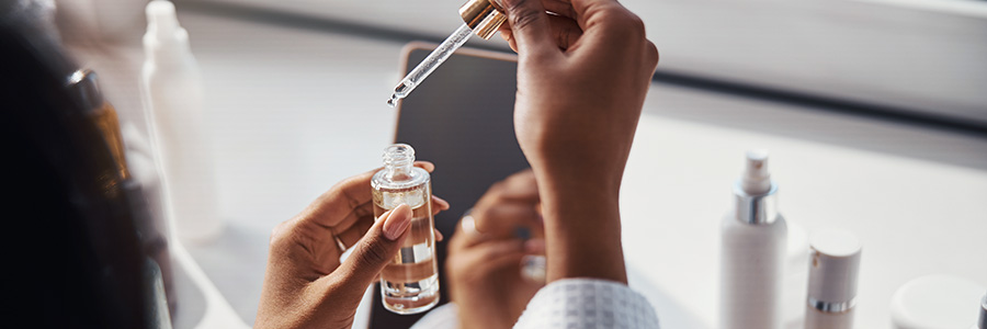 A closeup of a clinical technician dispensing a liquid from an eye dropper into a small bottle.