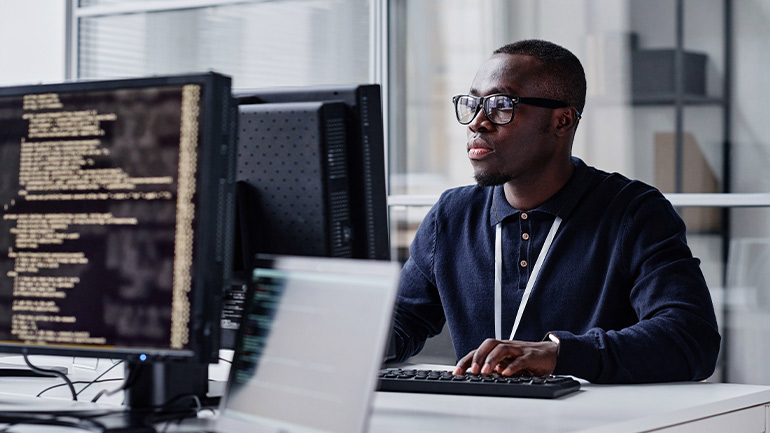 A person in front of a keyboard programming on a computer.