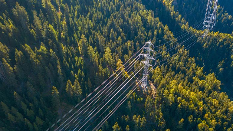 Vue aérienne de lignes de transport d’électricité qui traversent une forêt.