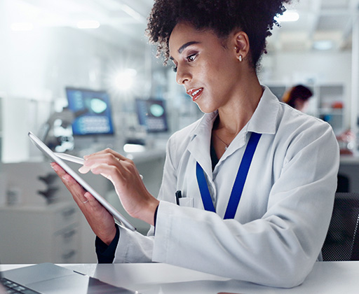  A woman in a lab coat studies information on a tablet computer.