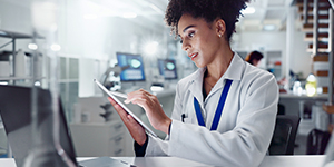  A woman in a lab coat studies information on a tablet computer.